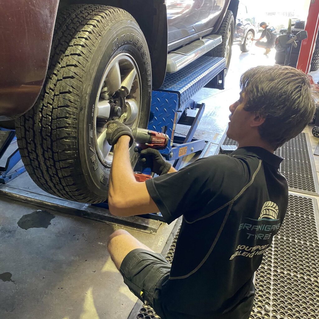 Branigans Burleigh Heads tyre shop team member putting back wheel.